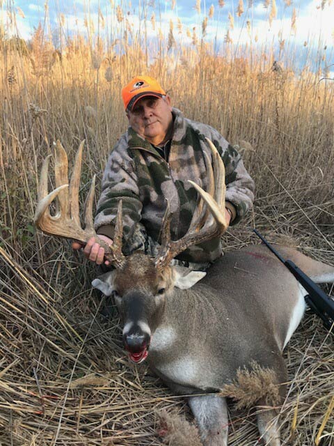older male hunter holding up giant buck antlers