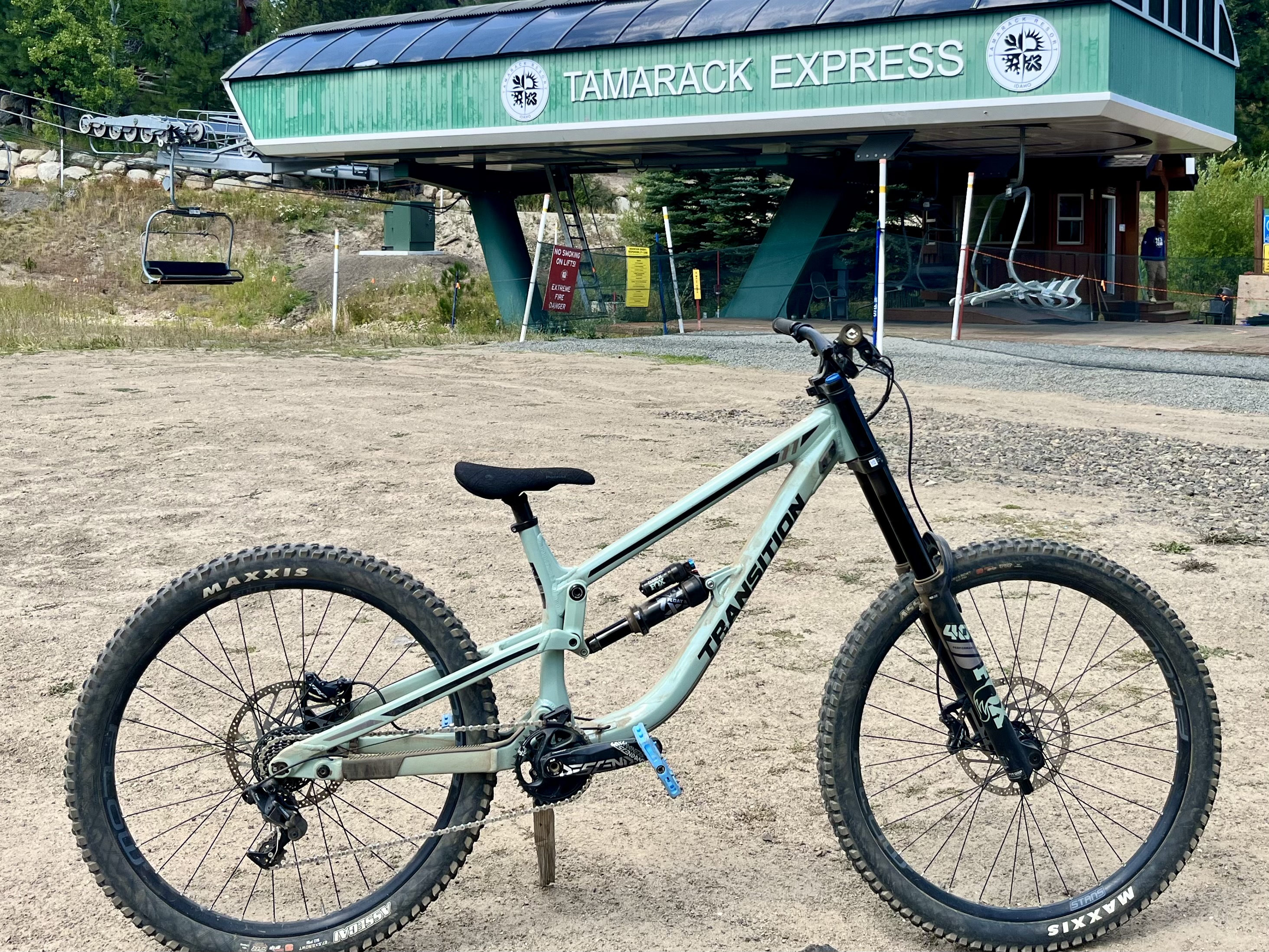 A downhill mountain bike sits in front of a lift.